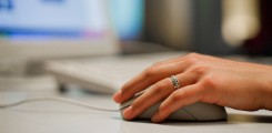 hand with computer mouse and part of a computer screen with medical information on it